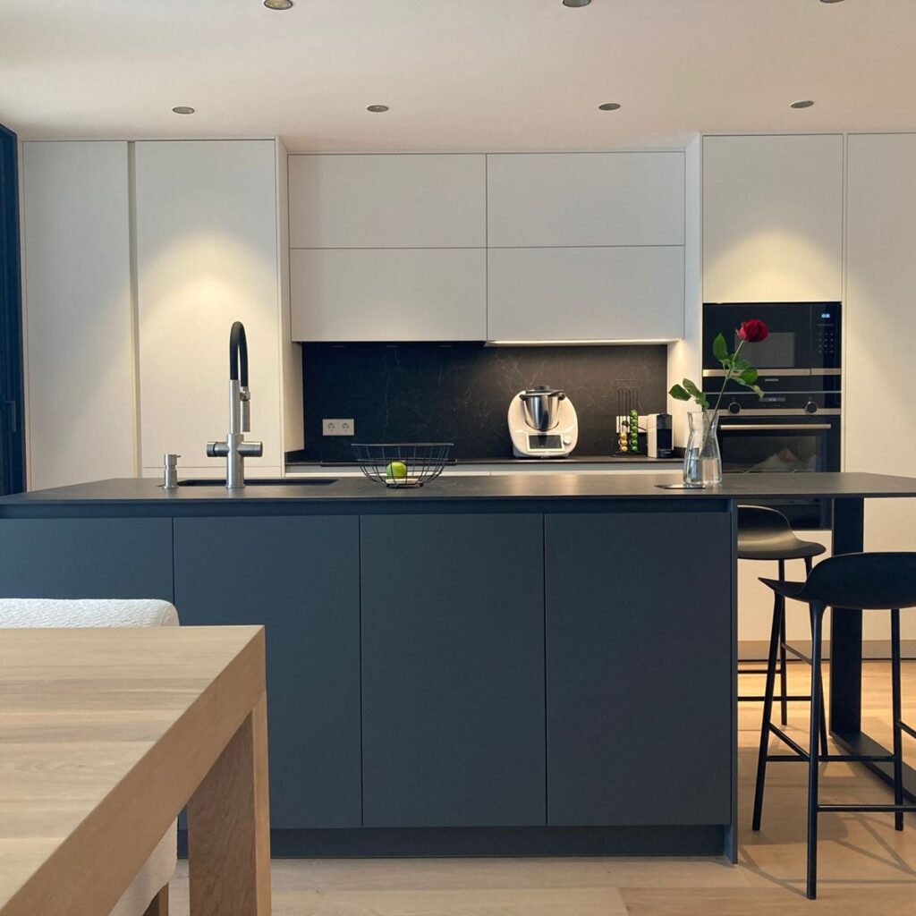 Cocina moderna en blanco y gris con isla central y electrodomésticos integrados.