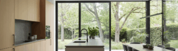 Cocina moderna con acceso al jardín mediante una puerta corredera de cristal de Sabaya
