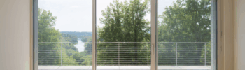 Puerta corredera de cristal de Sabaya con marco blanco que conecta el salón con la terraza, ofreciendo vistas panorámicas y máxima entrada de luz natural