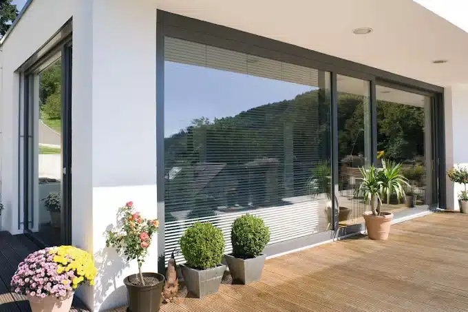 Cerramiento de terraza con correderas de aluminio de grandes hojas abierto a una terraza de madera