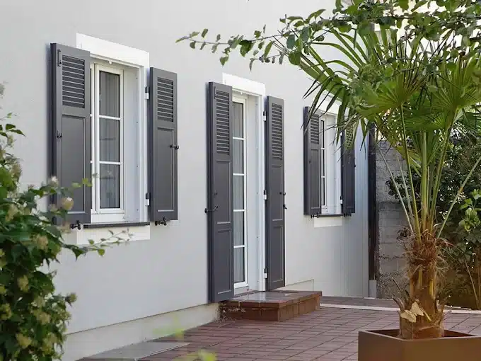 Fachada de vivienda con ventanas y puerta de PVC blancas y contraventanas de lamas grises